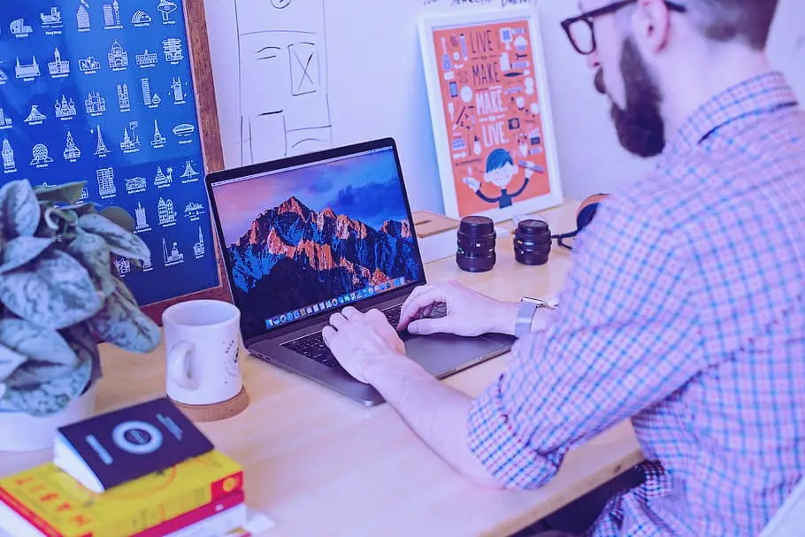 homem de óculos usando laptop mostrando como trabalhar com comunicação visual
