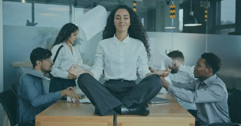 mulher em cima da mesa de escritório sorrindo e mantendo a calma em ambiente de trabalho tóxico usando a técnica do silêncio incômodo