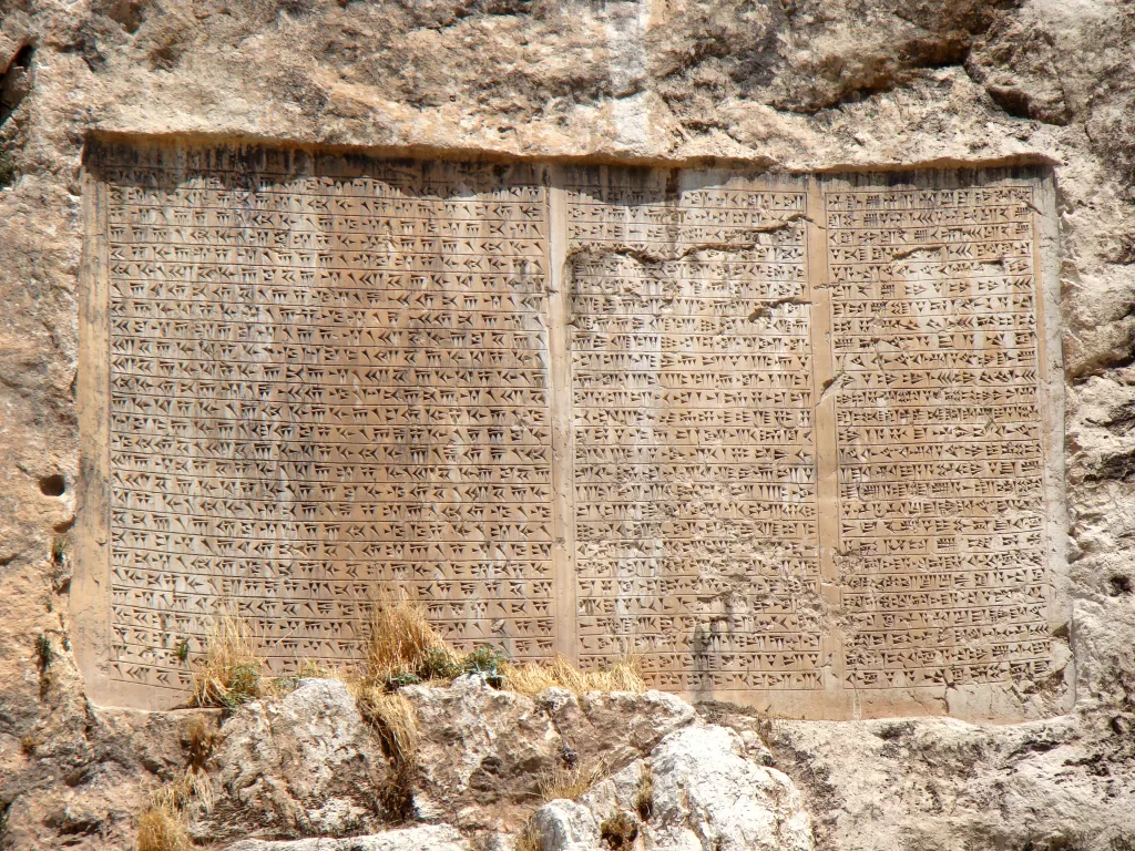 foto de uma parede imensa com mensagem de Xerxes registrada com escrita cuneiforme na pedra