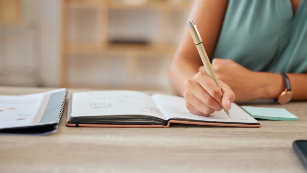 detalhe de mulher escrevendo em caderno para ilustrar coleção das melhores frases sobre escrever